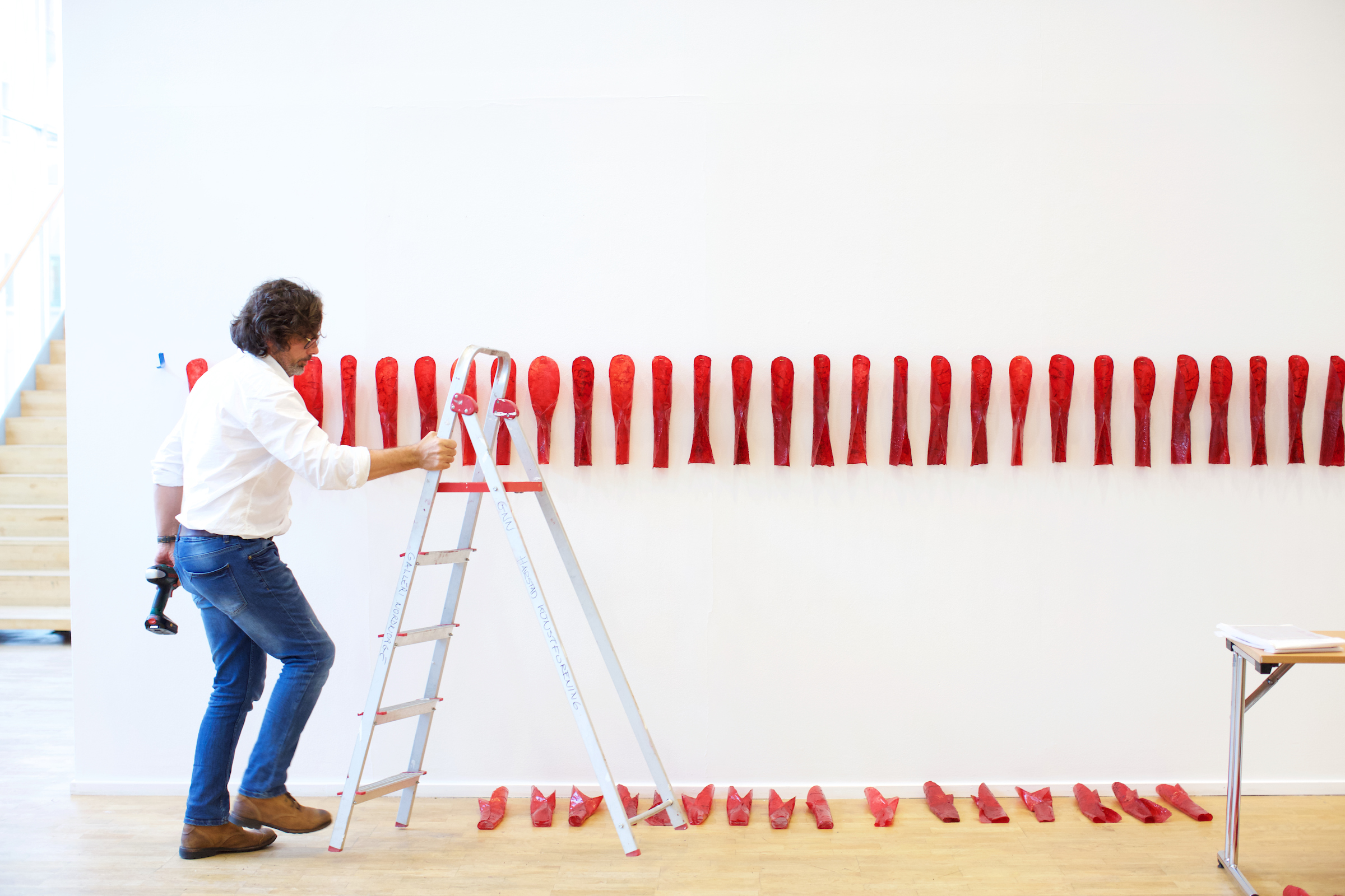 Artist Marek Ranis helps install "Red Curl" by Sonya Kellhier-Coombs.